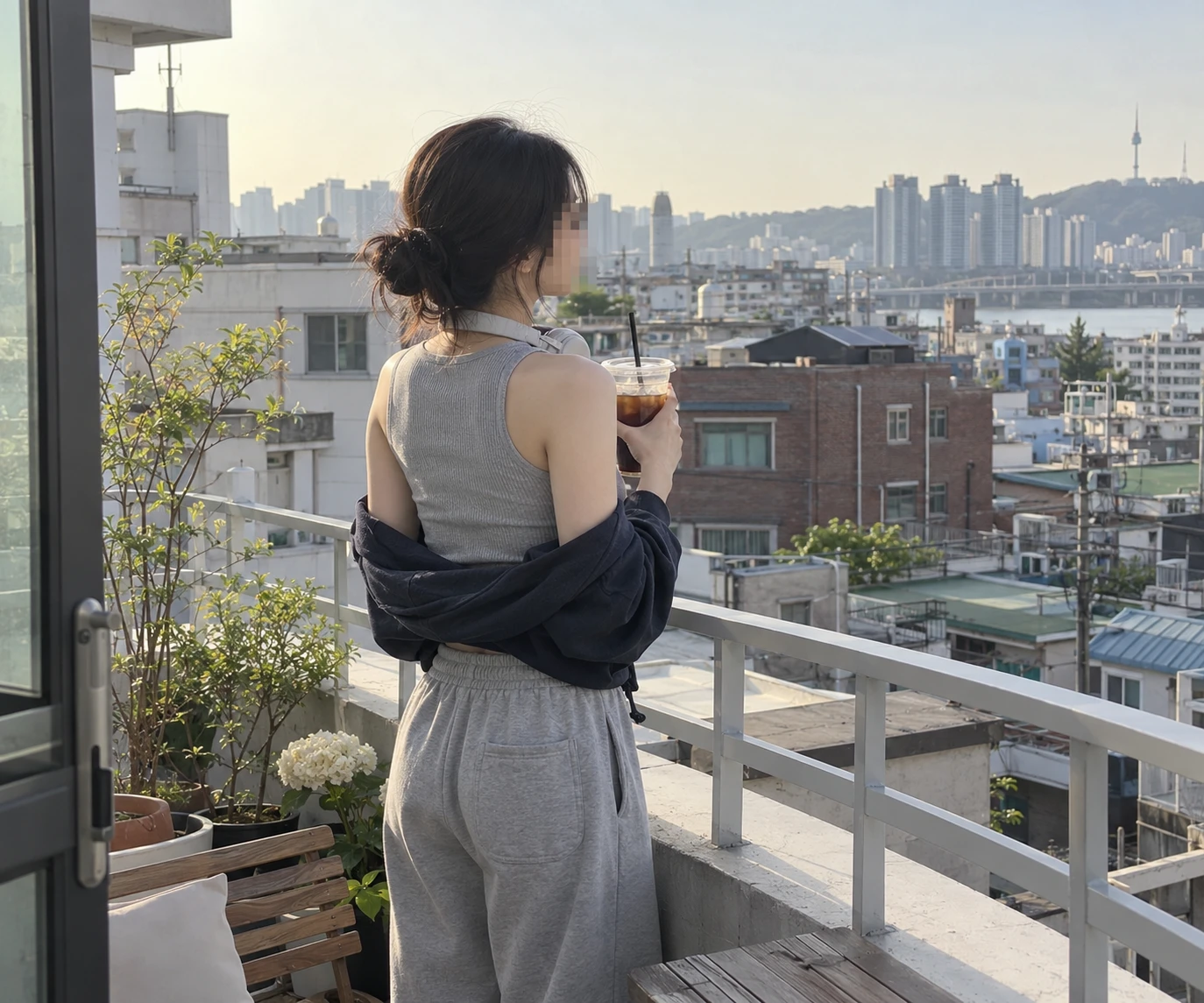테라스에서 음료를 들고 도심을 바라보는 여성